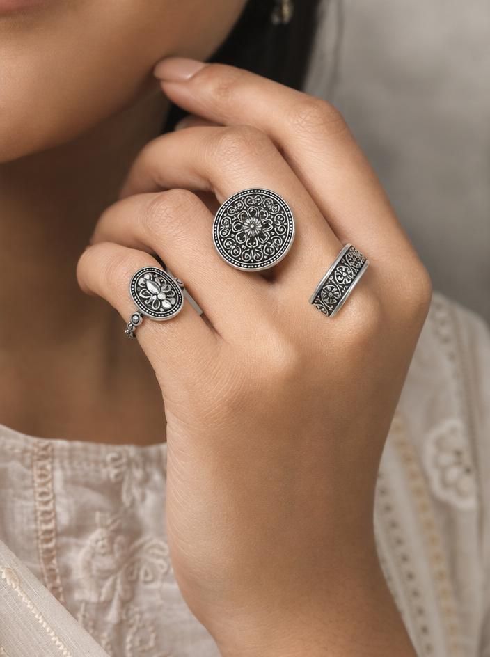 Three detailed silver rings on a model's hand